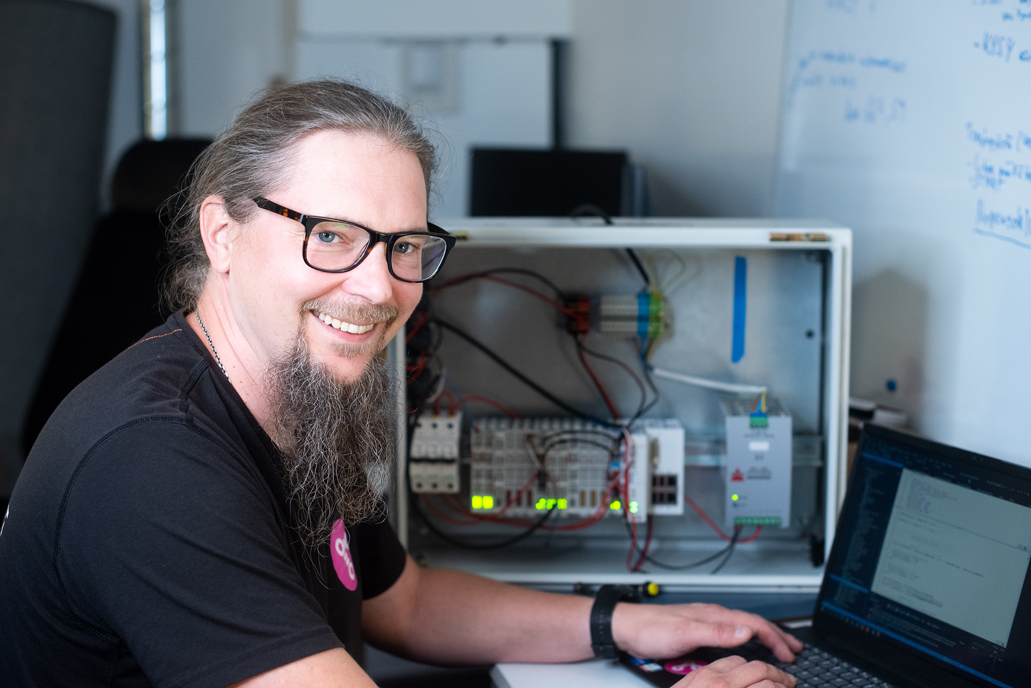 Engineer programming an automation system with a laptop in an industrial workspace.