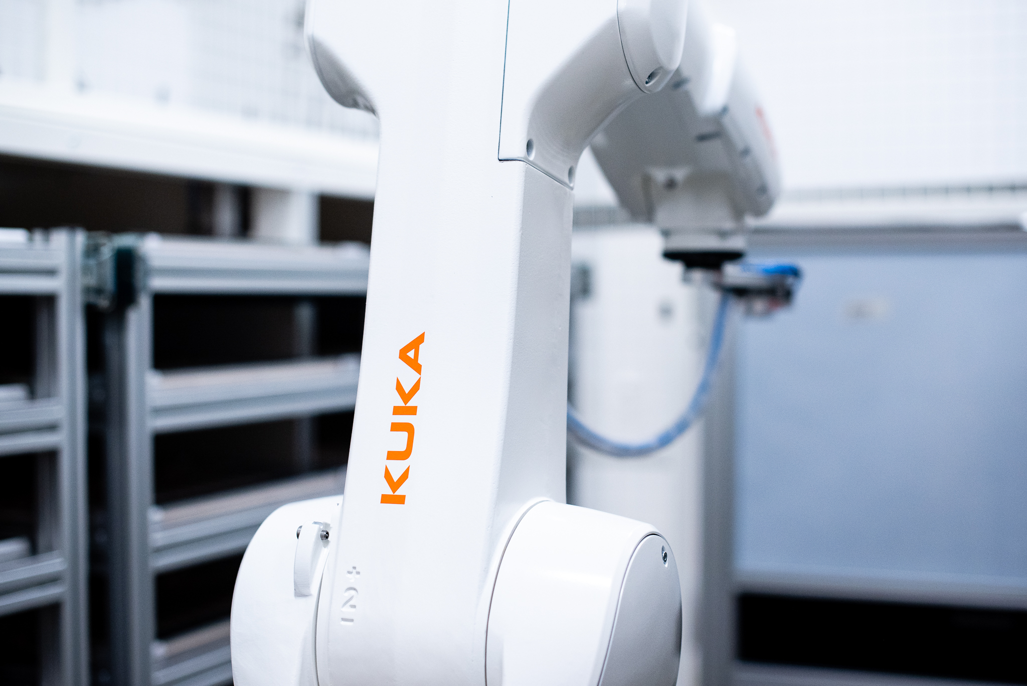 Close-up of a KUKA industrial robotic arm in an automated workspace.